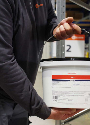 ELSEN Mitarbeiter hält Eimer mit Flamro Brandschutzspachtel